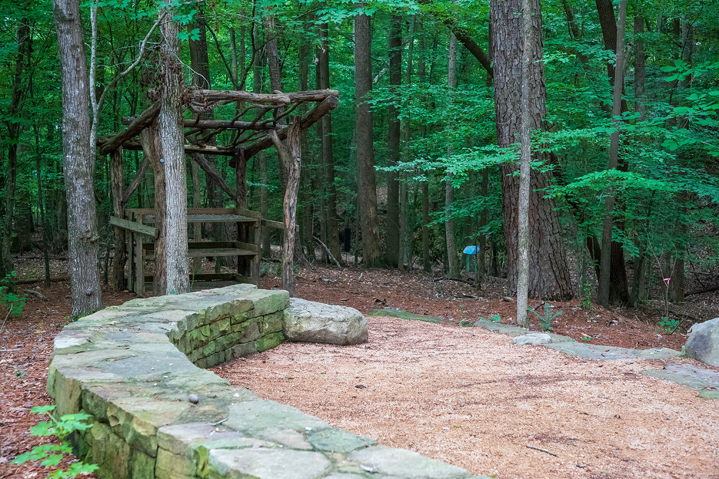 Outdoor classroom in the park showing a stone wall and wooden desk