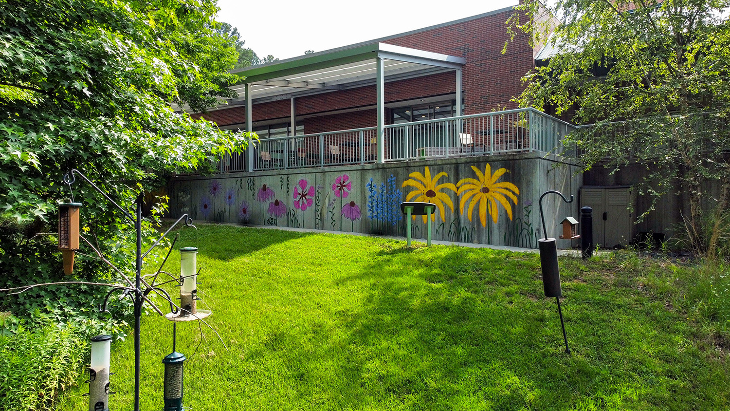 Terrace siding with colorful murals of flowers and hanging bird feeders in front