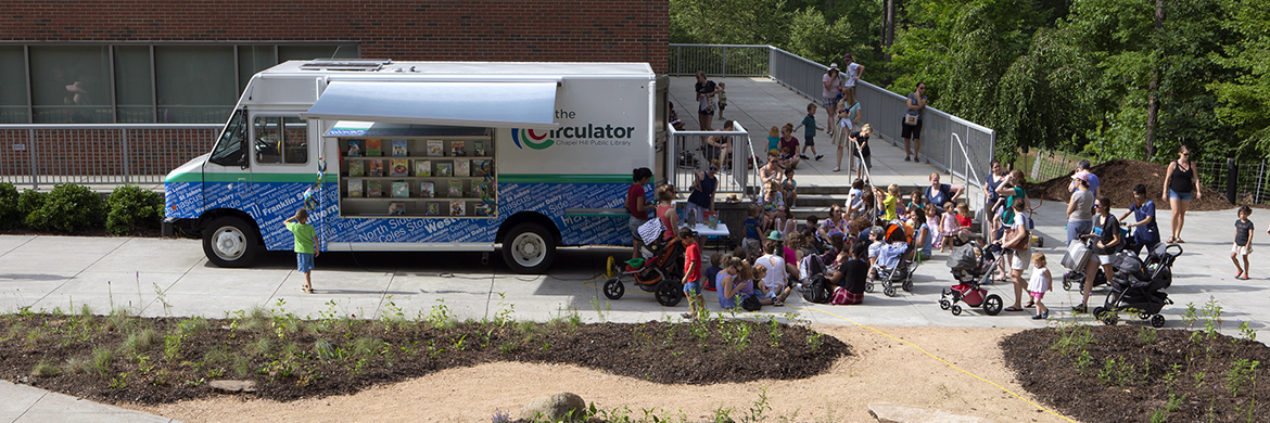 Image of the Circulator bus outside of a building with a large group of people crowded around