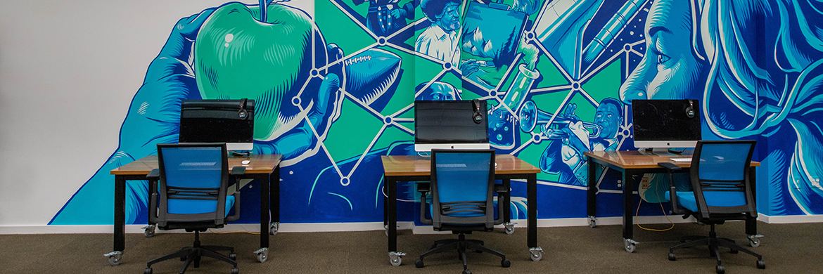 Tech lab showing three desktop computers against a colorful wall