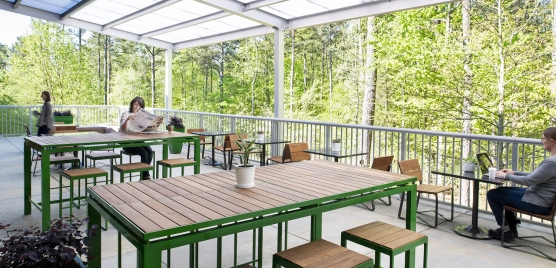 Patio area of the terrace showing wooden tables and seating with two patrons: one reading a newspapers and the other typing on a laptop
